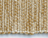 Close-up of handwoven gold and cream table runner's textured weave and surged edge.