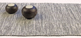 Handwoven table runner with a textured, ribbed weave in heathered shades of gray and white cotton.