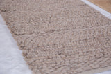 Natural beige undyed wool rug showing its thick, hand-woven looped texture.