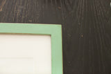 Mitered corner detail of a sleek mint green frame with a vintage-style finish.