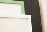 Sleek mitered corners of handmade wall art frames in white and mint green.