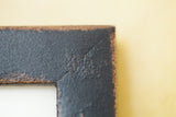 Close-up of a handmade frame's corner with a textured vintage black finish.