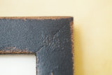 Textured black finish and distressed mitered corner of a vintage-style wall frame.