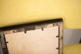Back corner of a handmade wall art frame with its plywood backing and metal hanger.