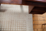 Softened beige and ivory tone-on-tone harlequin diamond pattern on a distressed Oushak rug.