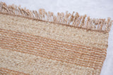 Handmade jute rug's woven texture, natural beige stripes, and fringed edge.
