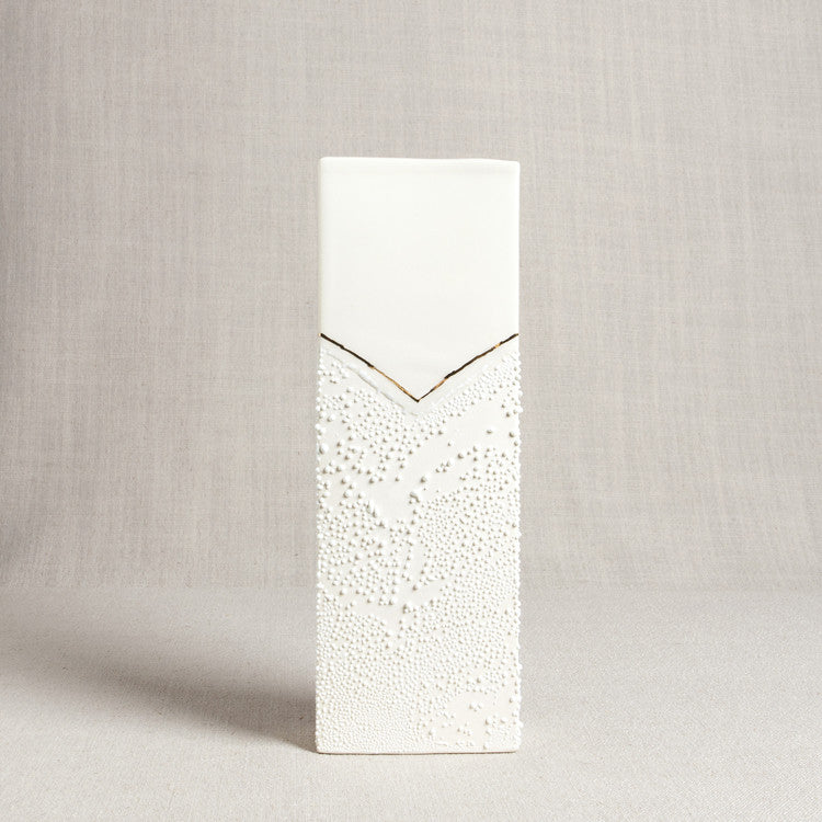 Rectangular porcelain vase with a smooth top, textured bottom, and a thin V-shaped gold accent line.