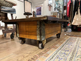 Dark reclaimed wood industrial coffee table cart with iron accents and casters.
