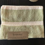 Close-up of handwoven lime and cream dish towel texture with Loomination tag.