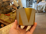 Modern scented soy candle in a hand-cast concrete vessel with a painted gold triangle pattern.