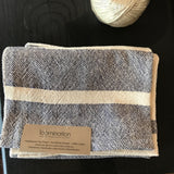 Close-up of handwoven navy and cream striped dish towel, highlighting its woven texture and brand label.