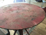 Worn red tabletop of the vintage industrial table, showing scratches and small rivets.
