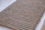 Close-up of Jace rug's handwoven jute texture with natural beige and blue stripes.