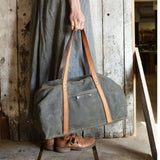 Moss green waxed canvas texture of the duffle bag, with contrasting leather handles.