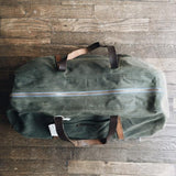 Peg and Awl Journey Duffle Bag: blue zipper detailing on rugged moss green waxed canvas.