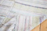 Folded vintage rag rug revealing reversible woven texture and colorful stripe dashes.