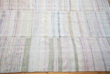 Close-up of vintage rag rug's soft texture, revealing sewn panels and subtle striped dashes.