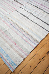 Soft, textured corner of vintage rag rug with ivory, blue, and pastel striped dashes.