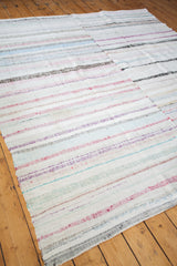 Frayed edge of vintage rag rug showing pastel stripes and woven texture.