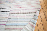Vintage rag rug folded, revealing reversible stripes of ivory, blue, red, and charcoal.