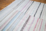 Vintage rag rug showing sewn pieces, with textured stripes of ivory, blue, red, charcoal.