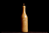 Lit natural beeswax candle in an antique bottle shape with an embossed lion.