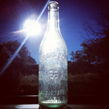 Antique glass bottle with embossed lion and brewery text, strongly backlit.