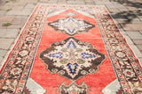 Vintage red Turkish runner, ornate central medallion in cream, blue, and brown tones.
