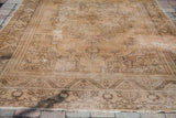Blanched vintage Oushak rug with sun-faded wheat field, floral drawing, lower border, and fringe.