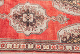 Vintage Oushak rug corner detail: madder root red field, charcoal bronze medallion, floral beige border.