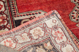 Vintage Oushak rug corner revealing madder root red pile, geometric charcoal-bronze border, and woven back.