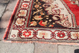 Vintage Oushak rug corner with madder root red border, charcoal bronze field, and fringe.