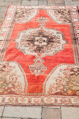 Vintage Oushak rug bottom corner, showing rust field and beige floral spandrel.