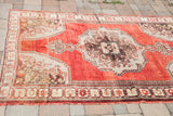 Vintage Oushak rug's lower border, madder root red, charcoal bronze, and beige motifs.