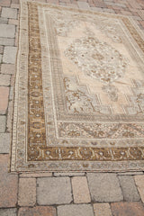 Bronze geometric border details and faded beige corner of vintage Oushak rug.