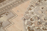 Vintage Oushak carpet section, faded beige field with silver-grey and bronze stylized motifs.