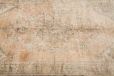 Sun-faded terra cotta field of the Oushak carpet with blanched charcoal and sage motifs.