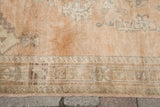 Blanched beige and charcoal geometric border patterns on sun-faded terra cotta Oushak.