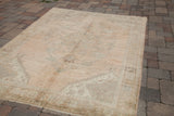 Sun-faded terra cotta vintage Oushak carpet corner with blanched geometric border and fringe.