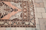 Vintage Oushak rug corner, showing peach field with brown and beige curvilinear motifs and borders.