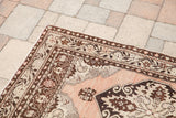 Peach vintage Oushak rug corner with traditional brown and beige stylized border motifs.