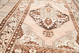 Vintage Oushak rug detail showing curvilinear medallion and scrolling brown motifs on a peach field.