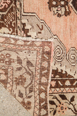 Vintage Oushak rug corner with peach pile, woven back, and fringed edge details.