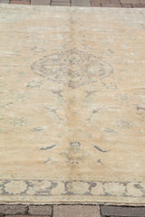 Vintage Oushak field with faded pastel earth tones and subtle mint-green motifs.