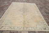 Soft pastel mint-green corner spandrels and muted border of the Oushak rug.