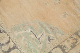 Faded pastel earth-tones and mint-green corner spandrel on the vintage Oushak rug.