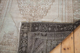Blanched vintage Oushak rug corner, showing faded light pile and dark woven back.