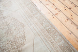 Vintage blanched Oushak rug corner, soft beige with geometric borders and faded motifs.