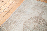 Muted beige medallion and curvilinear patterns on a blanched vintage Oushak rug.