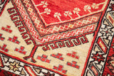 Detailed hand-knotted pile featuring zigzag and clover motifs in deep rust and cream.